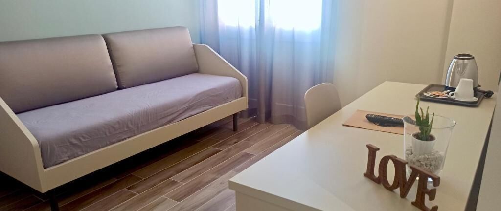 Una sala de estar moderna con un sofá, una mesa de centro, un control remoto y una bandeja con una taza y una planta.