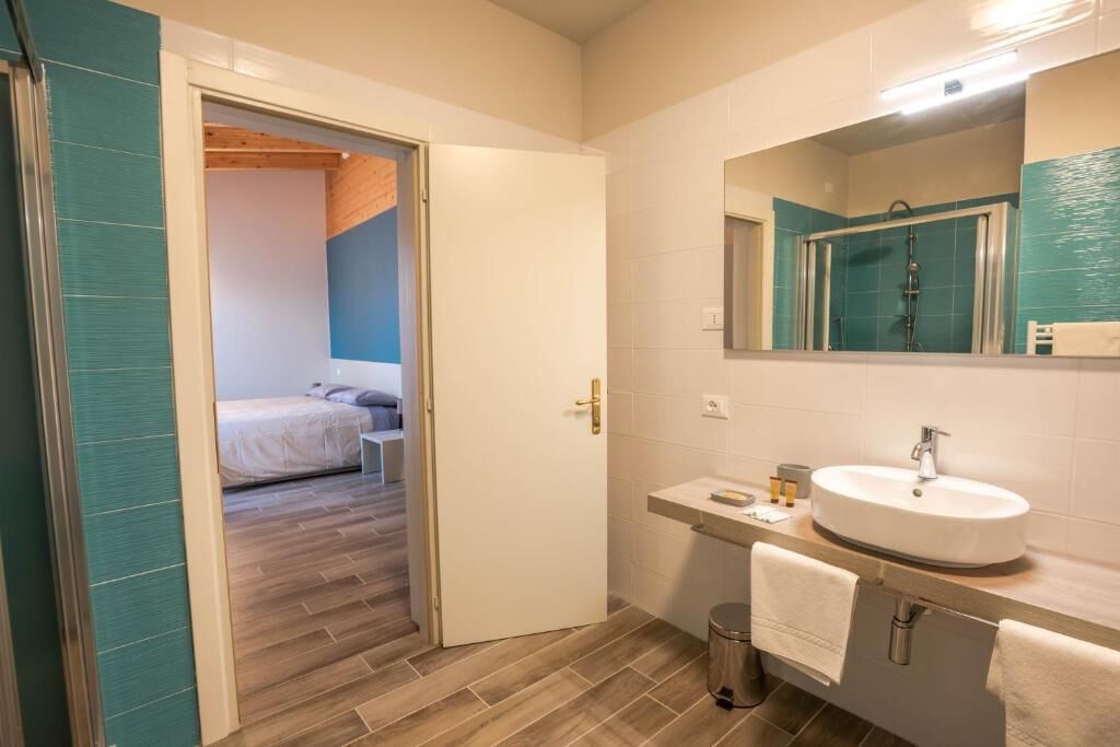 Uma casa de banho moderna com lavatório branco, espelho e chuveiro.