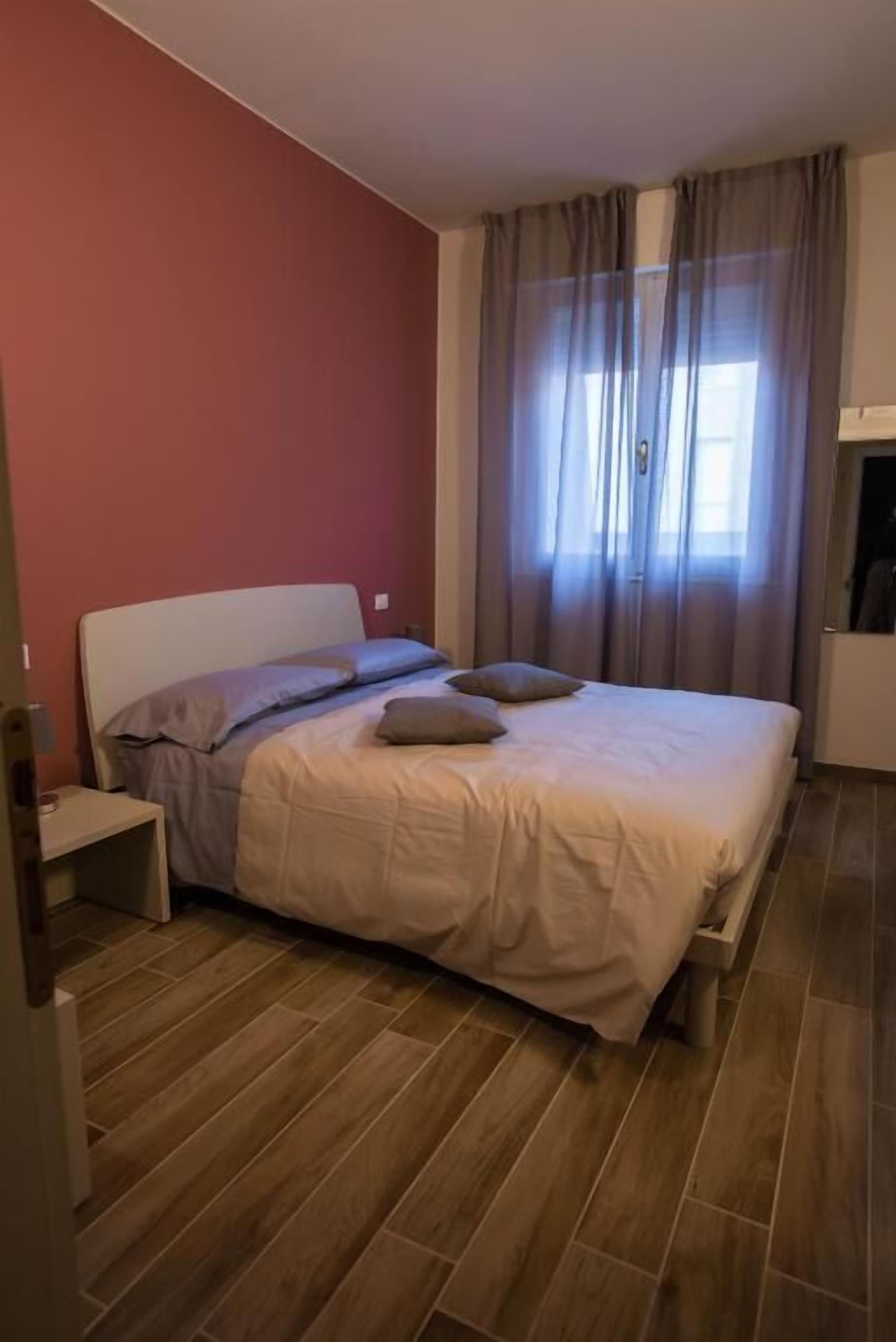 A bedroom with a bed, a nightstand, and a window with curtains.