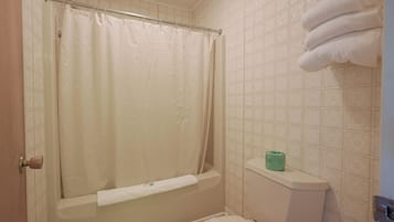 A bathroom with a bathtub, toilet, and a towel rack with towels.