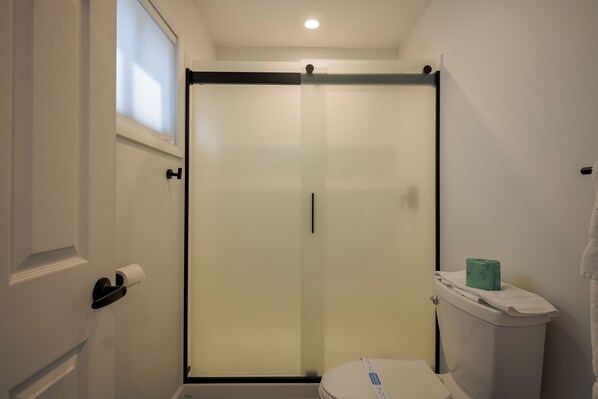 A bathroom with a toilet, a towel, and a toilet paper holder.
