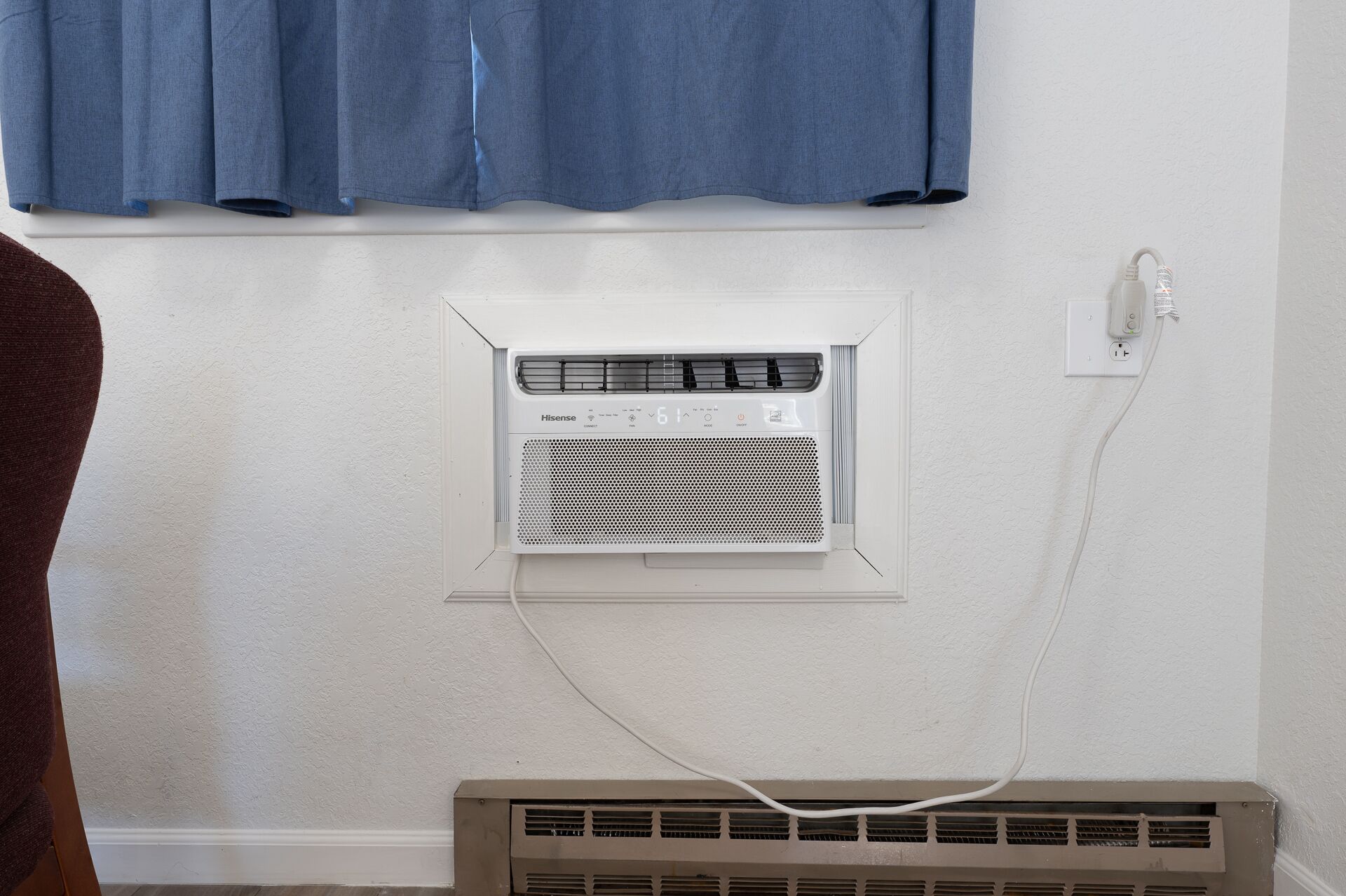 Un mur blanc avec un climatiseur fixé au mur et une prise de courant.