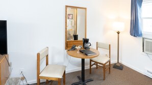 A hotel room with a round table, two chairs, a coffee maker, a lamp, and a large mirror. - Siesta Motel (Colfax)