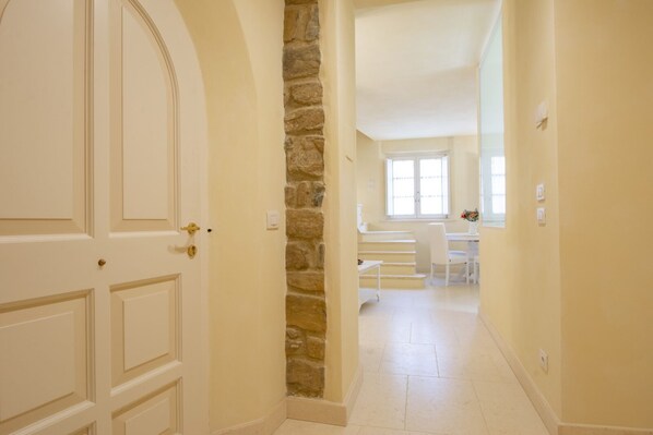 A hallway with a white door, a stone accent wall, and a dining area with a table and chairs.