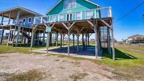 A two-story house with a wooden deck and a sign for rent.