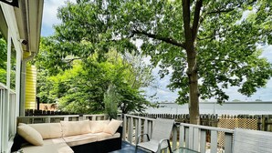 A covered outdoor seating area with a sofa and chairs, a small table, and a view of a body of water. - Casa Mia by the Braves Stadium In Smyrna Ga (Smyrna)