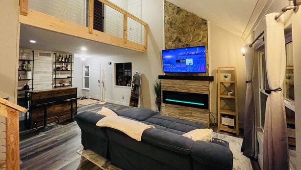 A high-ceilinged living room with a sofa, TV, and fireplace. - Casa Mia by the Braves Stadium In Smyrna Ga (Smyrna)
