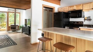 Una cocina moderna con armarios de madera, una isla central con taburetes, una estufa empotrada y un amplio ventanal con vistas al exterior.