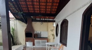 A covered outdoor area with a brick oven, white cabinets, and a small table.