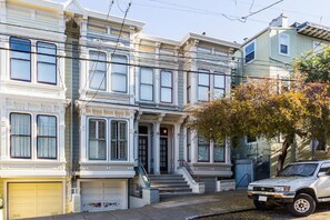 A row of Victorian-style houses with front porches and garage doors. - Private Garden Room in Victorian Home! (San Francisco)