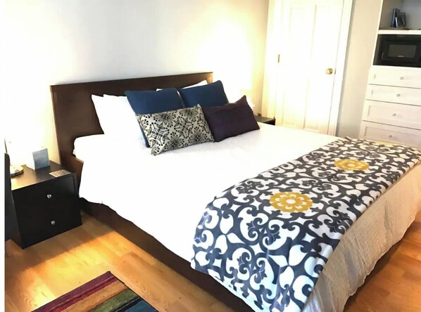A neatly made bed with a patterned bedspread, a dark headboard, and multiple pillows. - Private Garden Room in Victorian Home! (San Francisco)