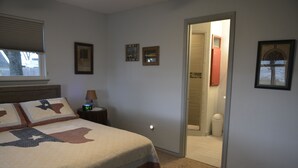 A bedroom with a bed, a nightstand, a clock, and a door leading to a bathroom. - Make memories in this cozy water front house on Eagle Mountain Lake. (Azle)