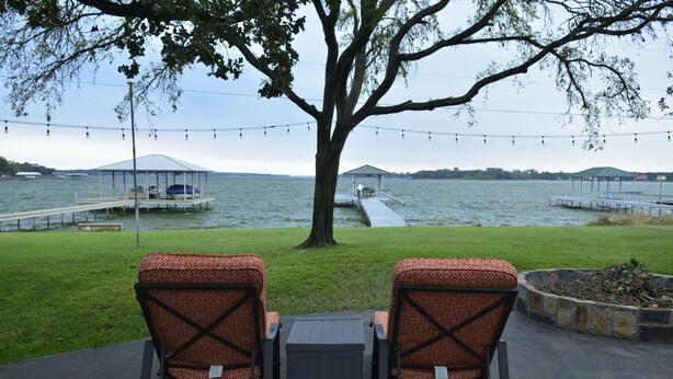 Two outdoor chairs facing a lake with a gazebo and dock in the background. - Make memories in this cozy water front house on Eagle Mountain Lake. (Azle)