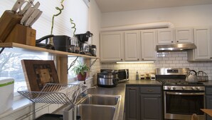 Una cocina moderna con armarios blancos, electrodomésticos de acero inoxidable y un ventanal con vistas al exterior.