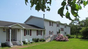 A two-story building with a porch and a staircase leading to the entrance. - Shepody Bay Inn (Shepody)