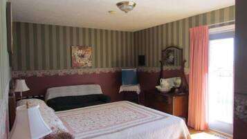 Une chambre à coucher avec un lit, une table de chevet, une commode, un miroir et une fenêtre avec des rideaux.