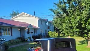 A vintage red car parked in front of a house with a red roof and a mailbox. - Shepody Bay Inn (Shepody)
