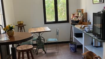 A compact kitchen with a dining area, a large window, and a television.