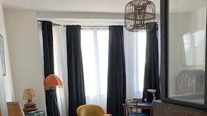 Quarto de hotel com cama, duas cadeiras, escrivaninha, luminária e piso estampado.