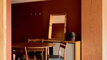 A dining area with a wooden table and chairs, a mirror, and a small cabinet.