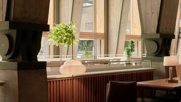 A modern interior with wooden panel walls, large windows, and a seating area with tables and chairs.