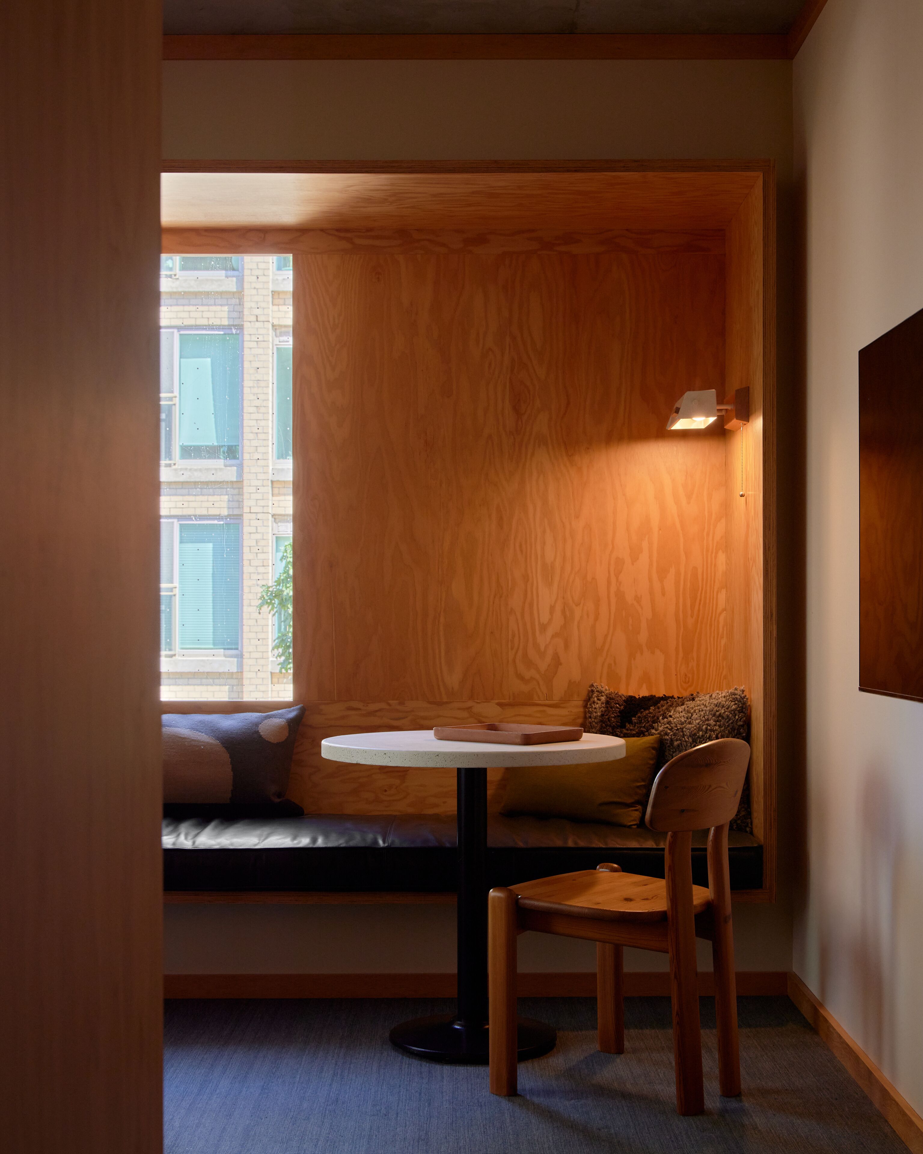 Een knus hoekje met een ronde tafel, een comfortabele bank en een houten stoel.