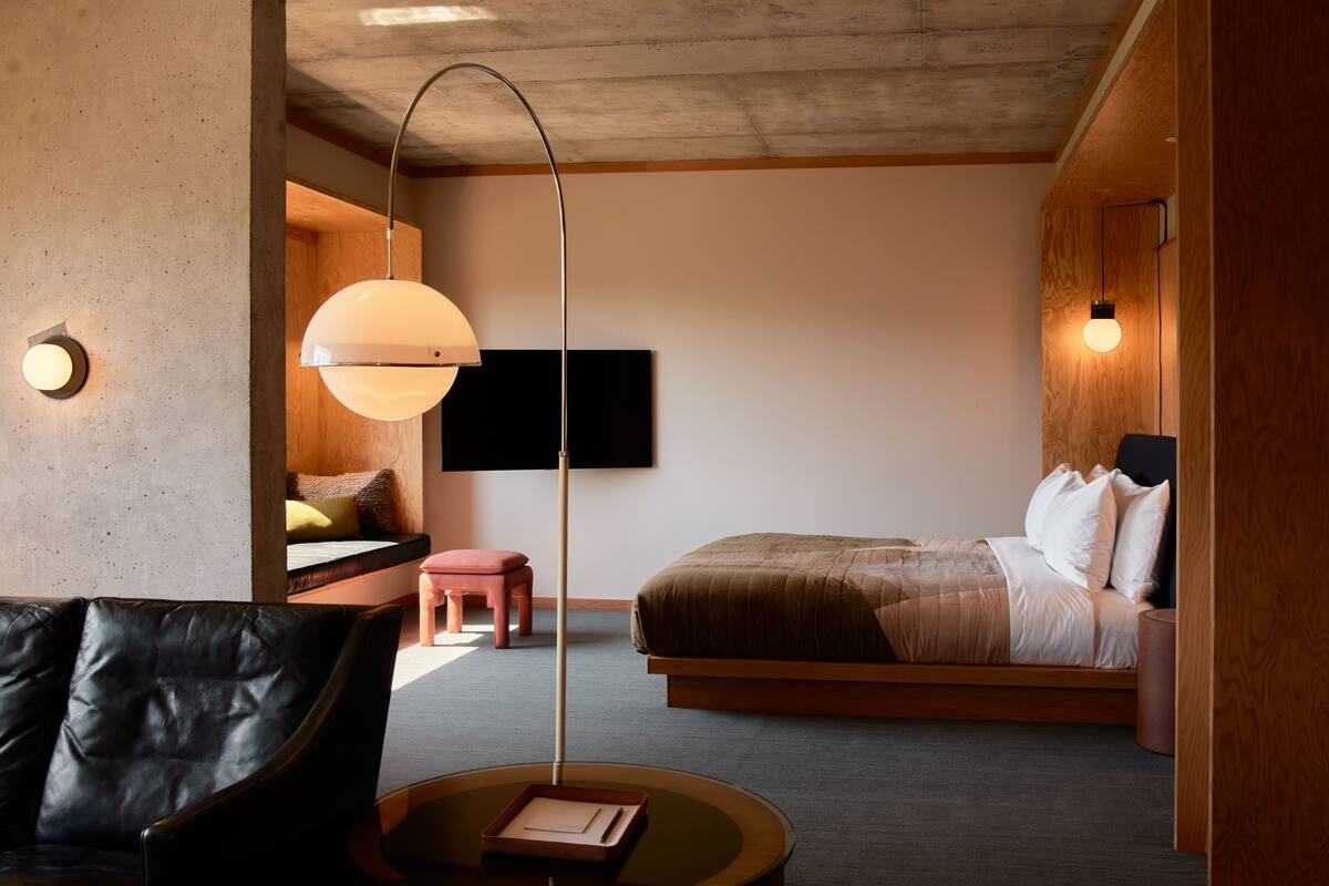 Un dormitorio moderno con cama, sofá, mesita y televisor.
