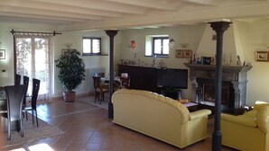 A living room with a sofa, chairs, a dining table, a TV, and a fireplace. - Villa Giulia - Homelike Villas (Appignano)