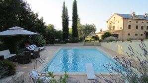 A rectangular swimming pool with a ladder, surrounded by lounge chairs and a pergola. - Villa Giulia - Homelike Villas (Appignano)