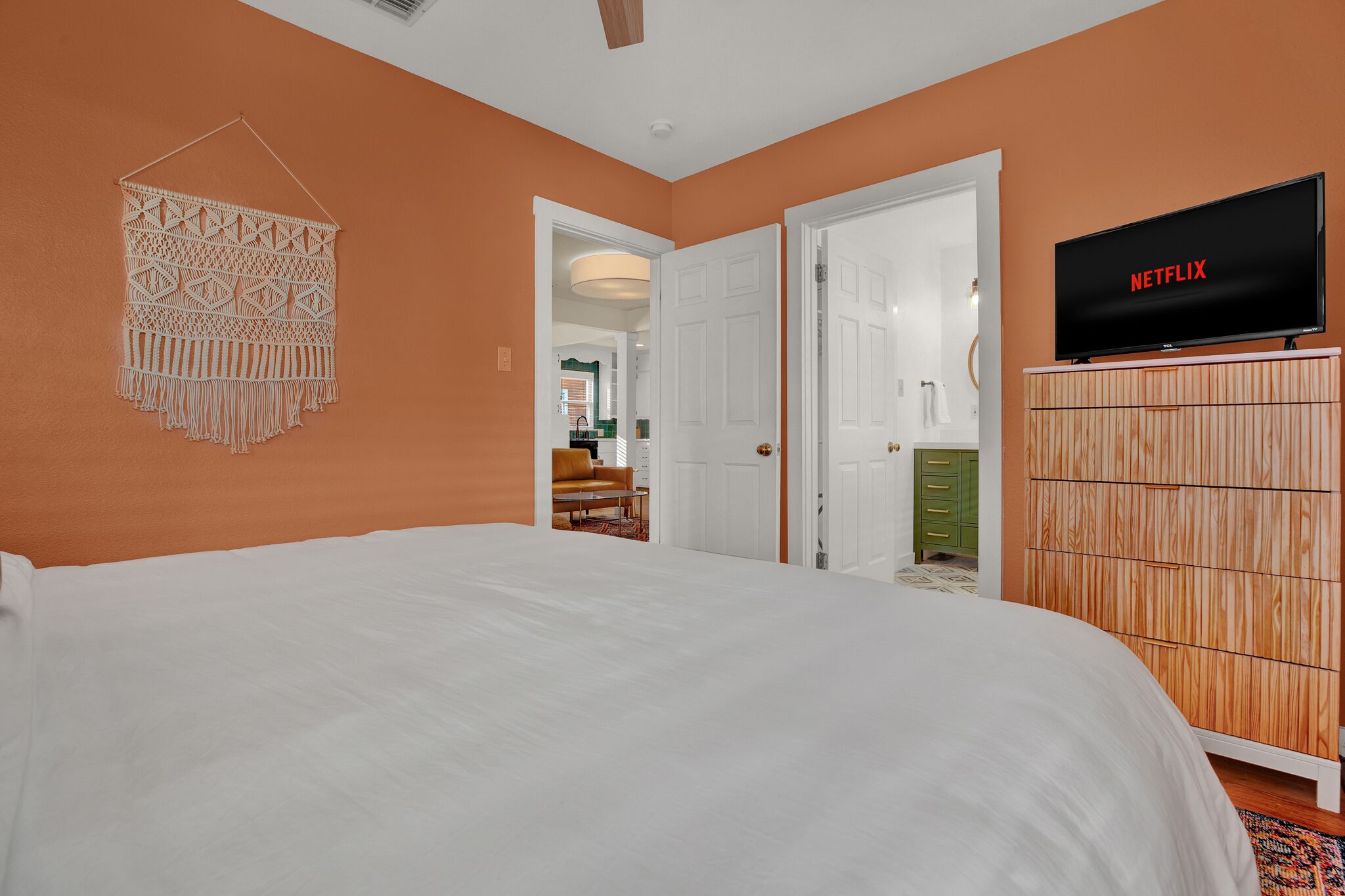 Un dormitorio con cama, un televisor de pared mostrando 'NETFLIX' y un armario de madera.