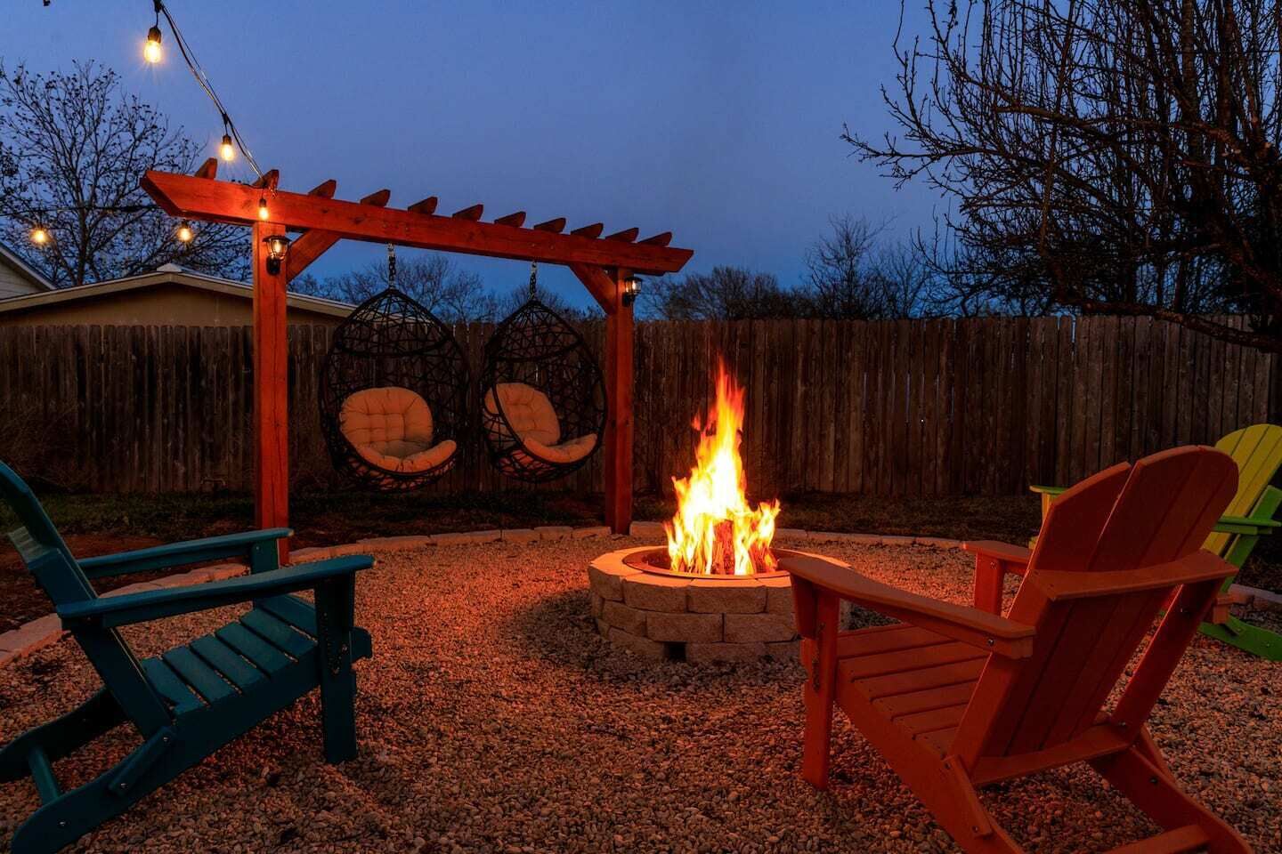 Patio trasero con un hogar, dos mecedoras y una pérgola de madera.