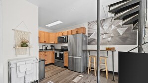 A modern kitchen with wooden cabinets, stainless steel appliances, and a small wooden table with stools. - The Alpenglow Loft - 1 Bed/1Bath- Radiant Charmer (Anchorage)