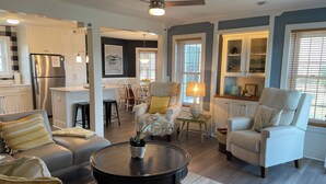 A modern living room with a sofa, armchairs, a coffee table, and a dining area with a table and chairs. - Vitamin Sea-Beautiful Oceanfront-3 Bedroom Condo Located in Duck, NC. (Duck)