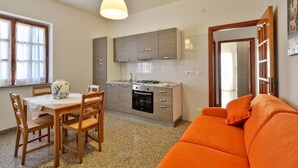 Un espace de vie compact comprenant un coin cuisine, un coin repas avec une table et des chaises, et un canapé.