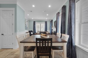 A dining room with a long wooden table, white chairs, and a fireplace. - 🌊Dip Your Toes: Pet-Friendly Cottage w/ Intracoastal Access and Community Pool (Navarre)