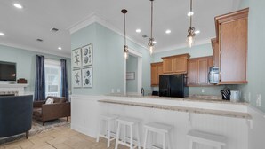 Una cocina moderna con una isla central, armarios de madera e iluminación colgante.