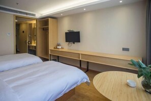 A hotel room with two beds, a desk, a TV, and a small round table with a plant. - Shucheng Saifu Hotel (Shucheng)