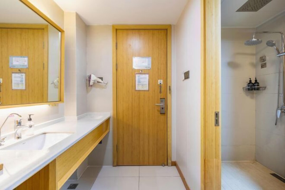 A bathroom with a wooden door, a white sink, and a shower area.