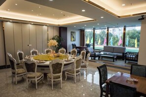 A dining area with a round table, chairs, and a view of the outdoors. - Shucheng Saifu Hotel (Shucheng)