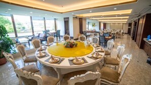 Un comedor espacioso con una mesa redonda grande rodeada de sillas ornamentadas, un mantel amarillo y un centro de mesa floral.