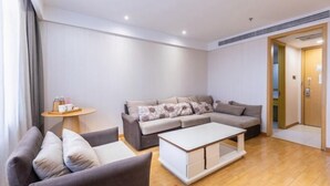 Una sala de estar moderna con un sofá gris, una mesa de centro blanca y una pequeña mesa redonda con una bandeja de objetos.