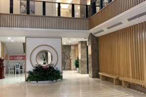 A hotel lobby with a central circular mirror, seating area, and a staircase. - Shucheng Saifu Hotel (Shucheng)