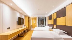 Una habitación de hotel moderna con suelo de madera, un banco largo, dos camas con sábanas blancas, un televisor de pantalla plana y un armario con combinación de madera y paneles oscuros.