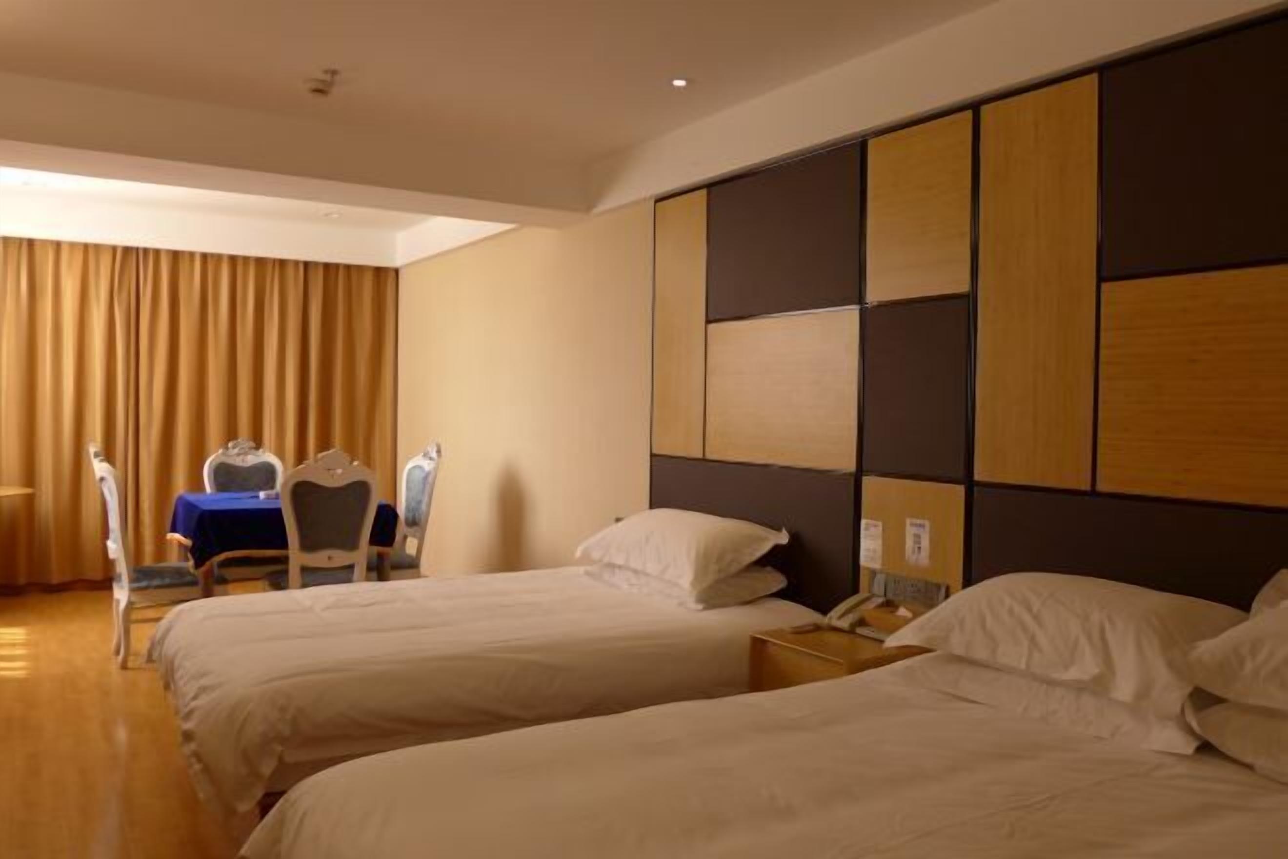 A hotel room with two beds, a desk, and a chair.