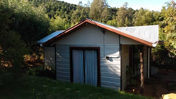 A small, single-story building with a sloped roof, a garage door, and a window.