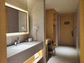 A modern bathroom with a large mirror, a sink, a hairdryer, and a towel rack. - Ji Hotel (Hangzhou)