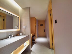 A modern bathroom with a large mirror, a hairdryer, and a towel dispenser. - Ji Hotel (Hangzhou)
