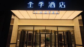 A hotel entrance with a revolving door and a neon sign above. - Ji Hotel (Hangzhou)