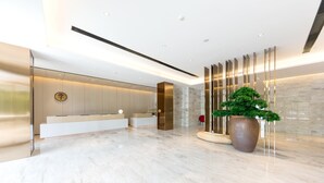 A modern lobby with a reception desk, a large potted plant, and a stone wall. - Ji Hotel (Hangzhou)