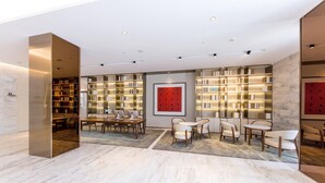 A modern library with bookshelves, a dining area with tables and chairs, and a large red artwork on the wall. - Ji Hotel (Hangzhou)